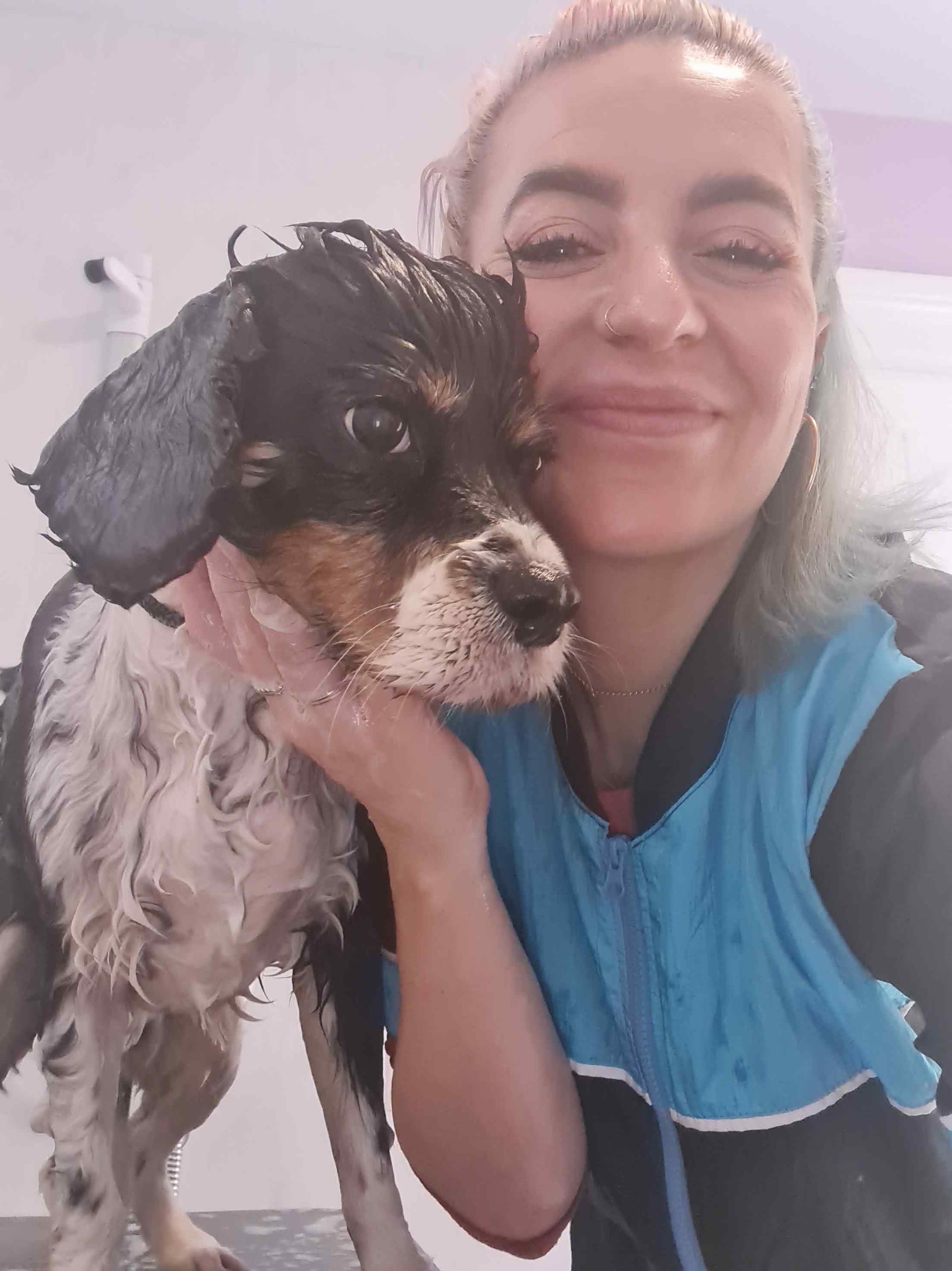 Pelin smiling with a wet spaniel mid-groom in her arms